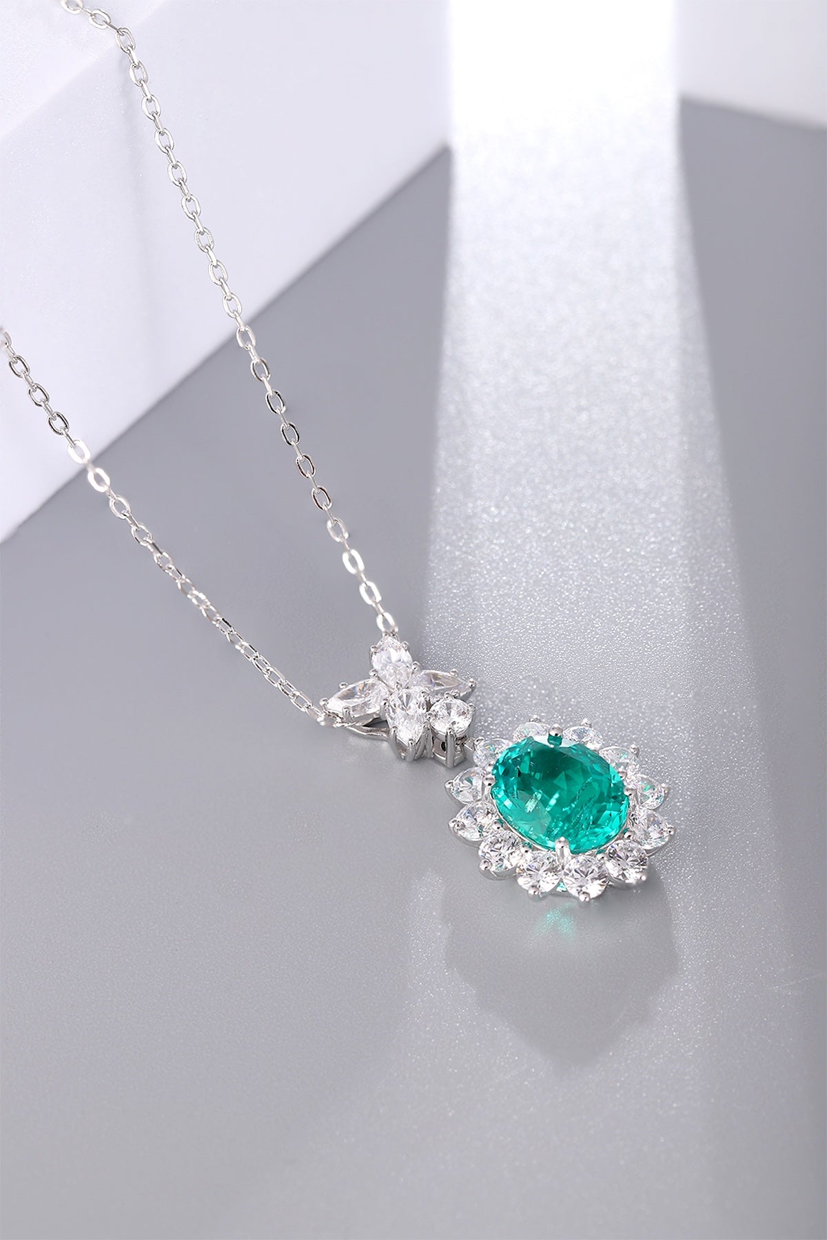 This S925 sterling silver necklace has a delicate design. Oval emerald with diamond halo, vibrant green, classic shape.
