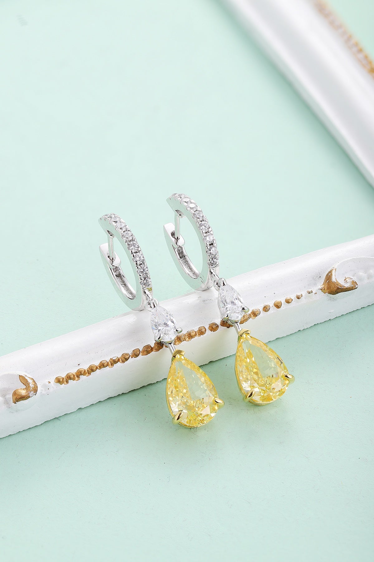 The S925 silver earrings feature a reliable clasp. Clear and yellow cubic zirconia in teardrop shape, lovely design.