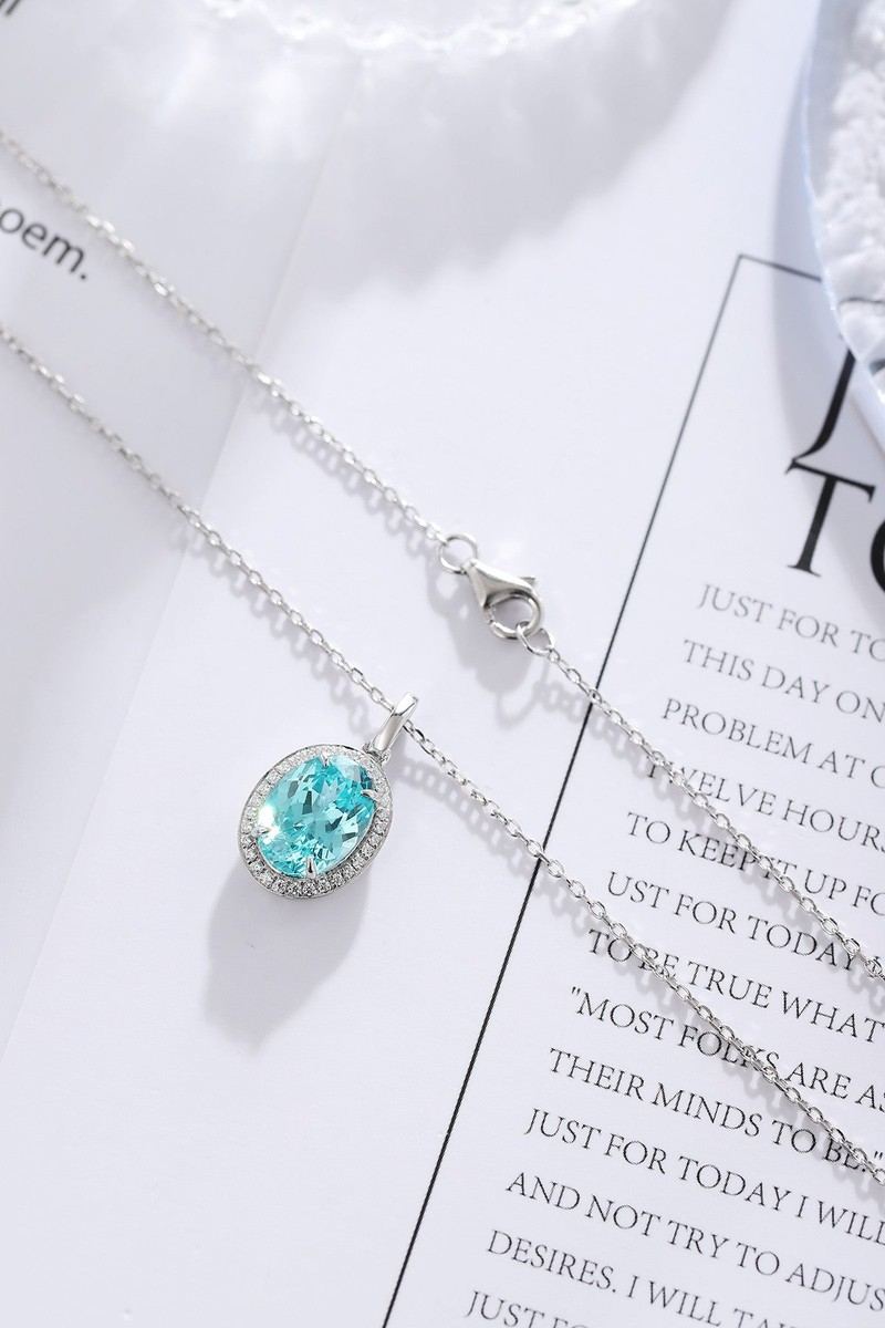 S925 silver necklace with reliable clasp. Shows an oval vivid - blue gem encircled by small diamonds, attractive.
